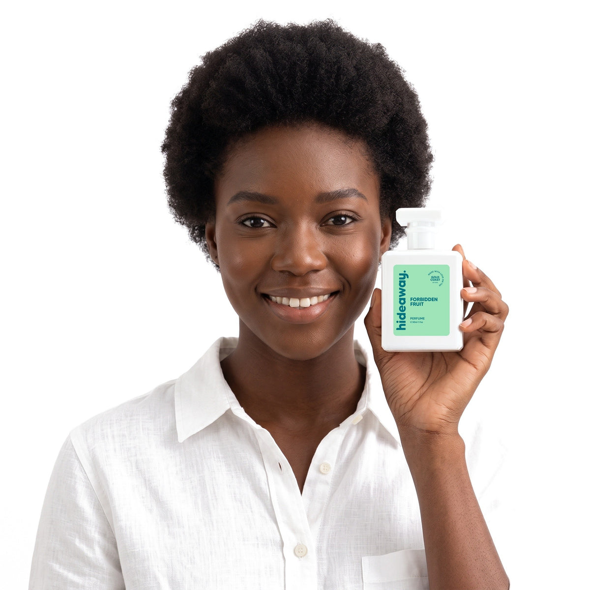 A smiling woman holding Hideaway. Forbidden Fruit perfume
