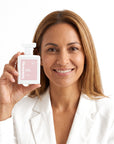 A smiling woman holding Hideaway. Ivory Bloom perfume