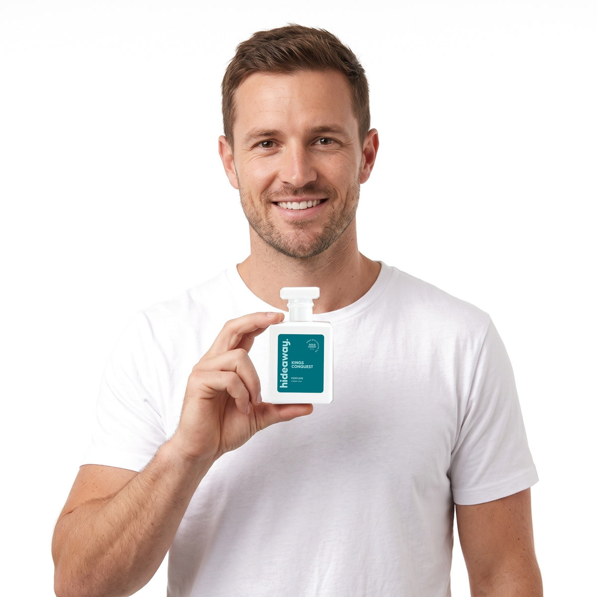 A smiling man holding Hideaway. Kings Conquest perfume