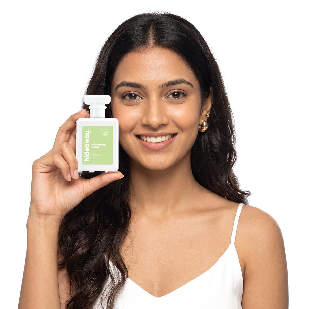 A smiling woman holding Hideaway. Kiwi Berry Bang perfume