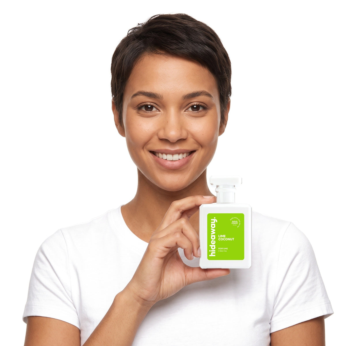 A smiling woman holding Hideaway. Lime Coconut perfume
