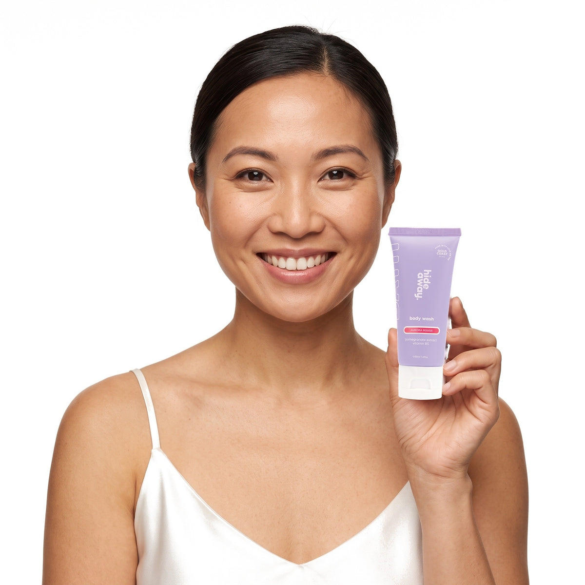 A smiling woman holding Hideaway. Aurora Rouge mini body wash