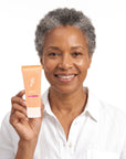 A smiling woman holding Hideaway. Aurora Rouge mini conditioner