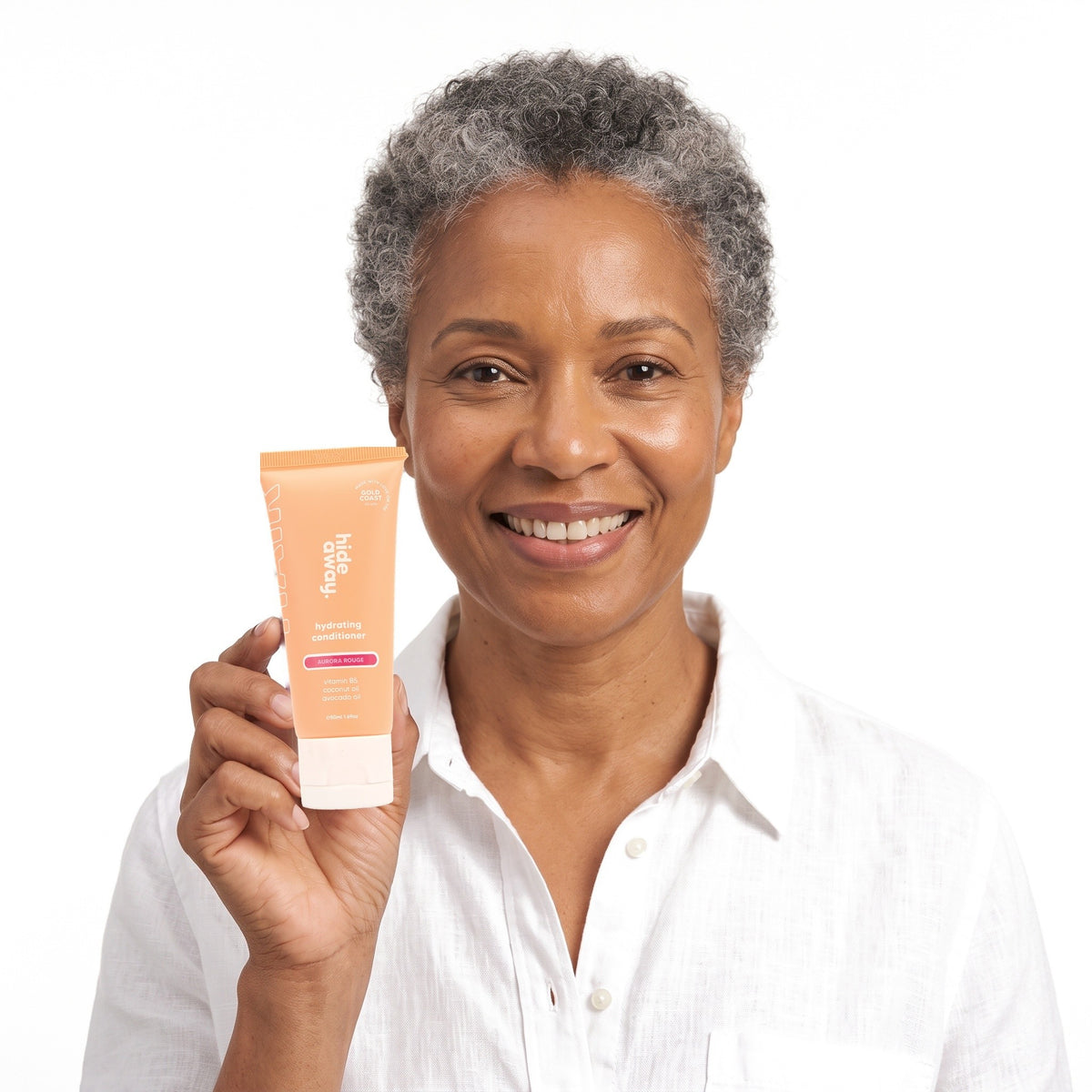 A smiling woman holding Hideaway. Aurora Rouge mini conditioner