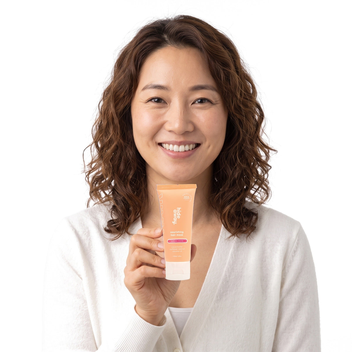 A smiling woman holding Hideaway. Aurora Rouge mini hair mask
