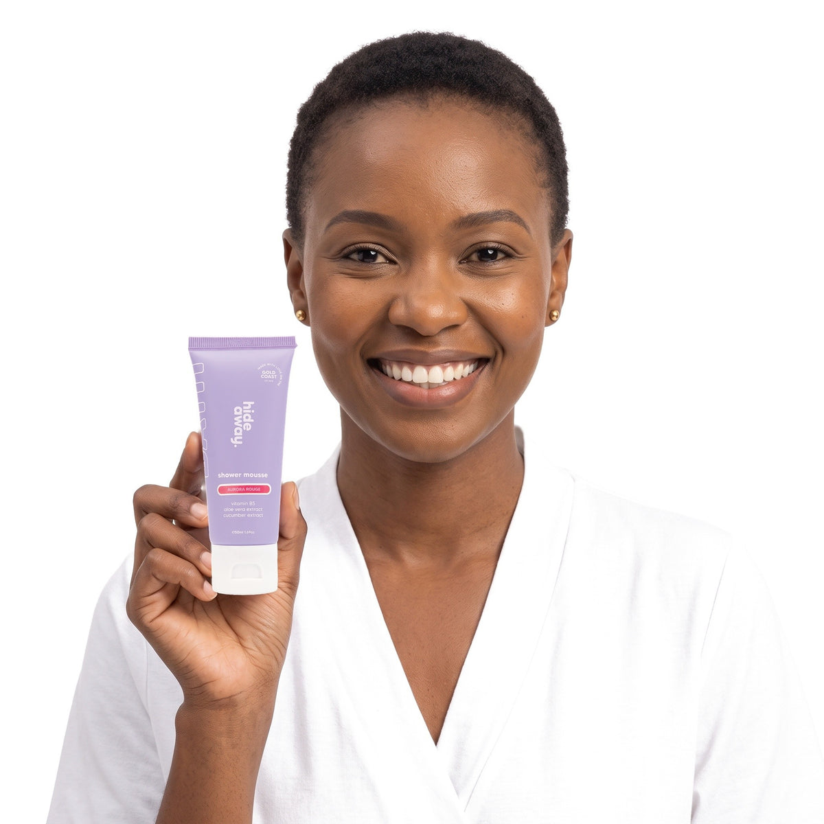 A smiling woman holding Hideaway. Aurora Rouge mini shower mousse
