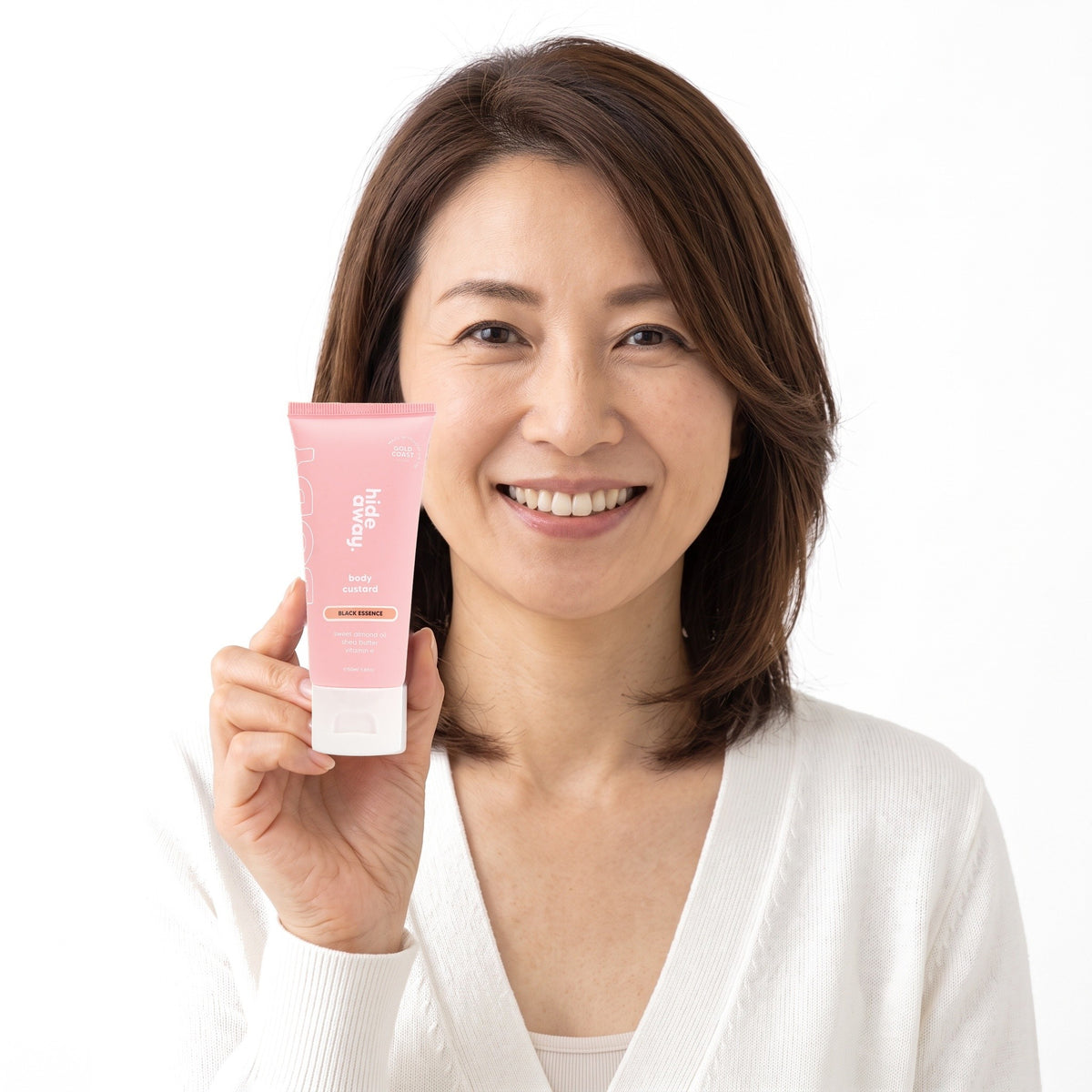 A smiling woman holding Hideaway. Black Essence mini body custard