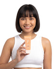 A smiling woman holding Hideaway. Black Essence mini conditioner