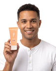 A smiling man holding Hideaway. Black Essence mini shampoo