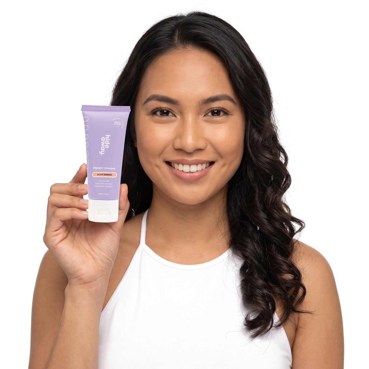 A smiling woman holding Hideaway. Black Essence mini shower mousse