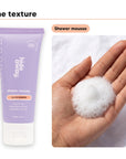 Shower mousse texture in an open palm, beside Hideaway. Black Essence mini shower mousse