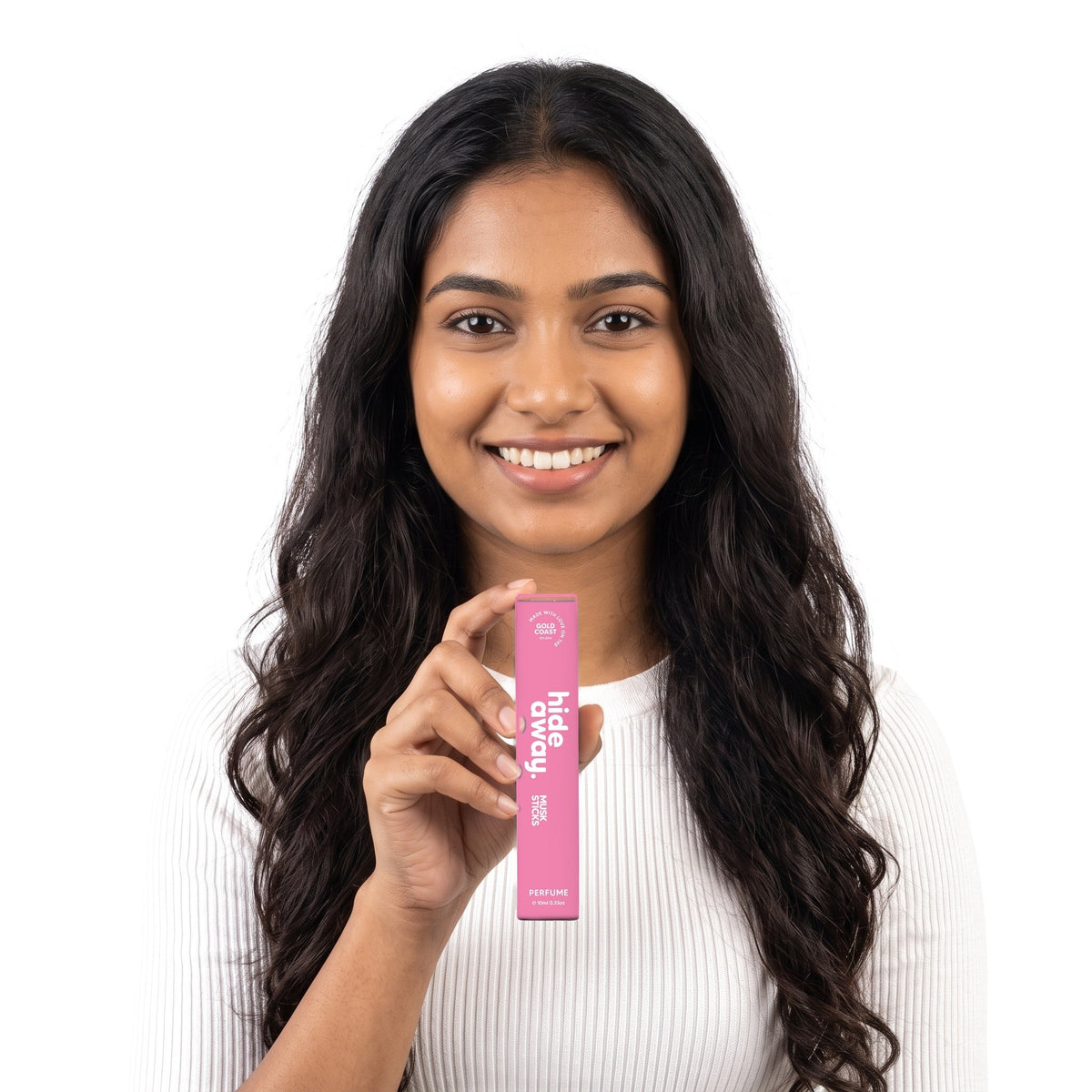 A smiling woman holding the Hideaway. Musk Sticks 10ml perfume box