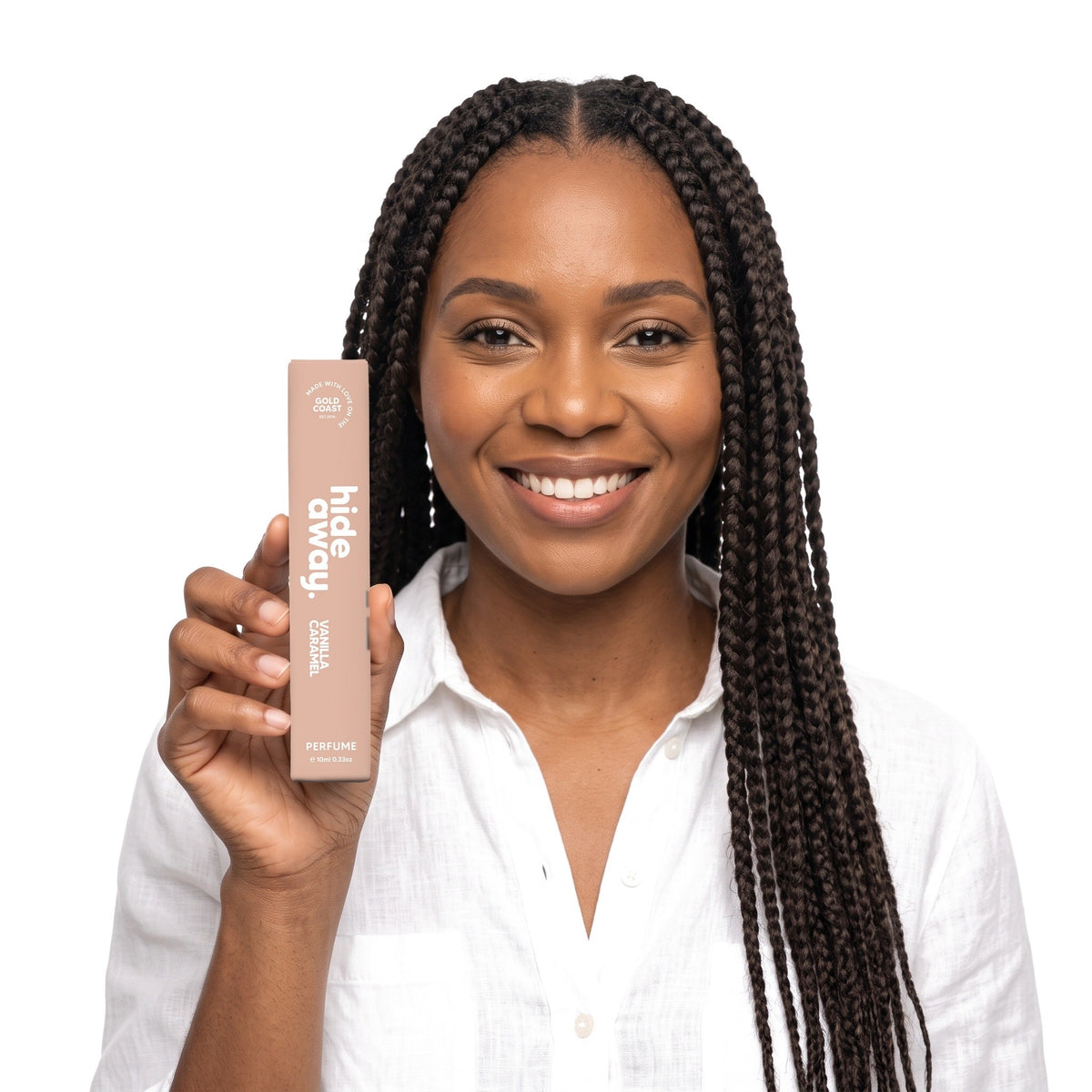 A smiling woman holding the Hideaway. Vanilla Caramel 10ml perfume box