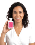 A smiling woman holding Hideaway. Pink Spice perfume