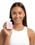 A smiling woman holding Hideaway. Rise & Shine perfume