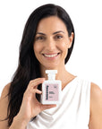 A smiling woman holding Hideaway. Smoke & Sugar perfume