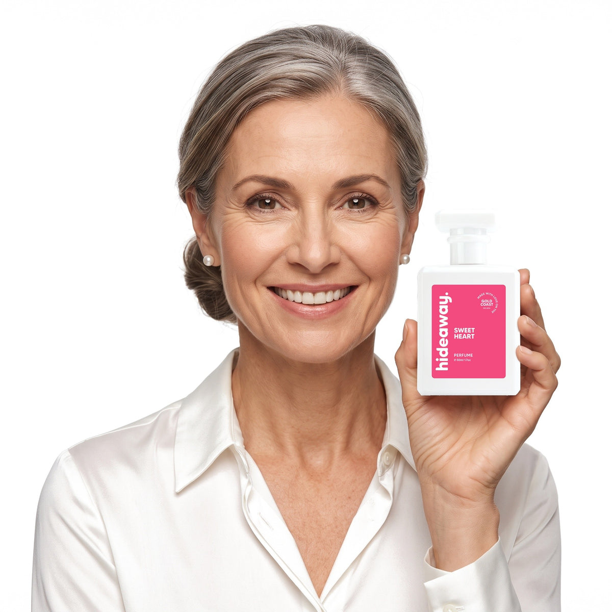 A smiling woman holding Hideaway. Sweet Heart perfume