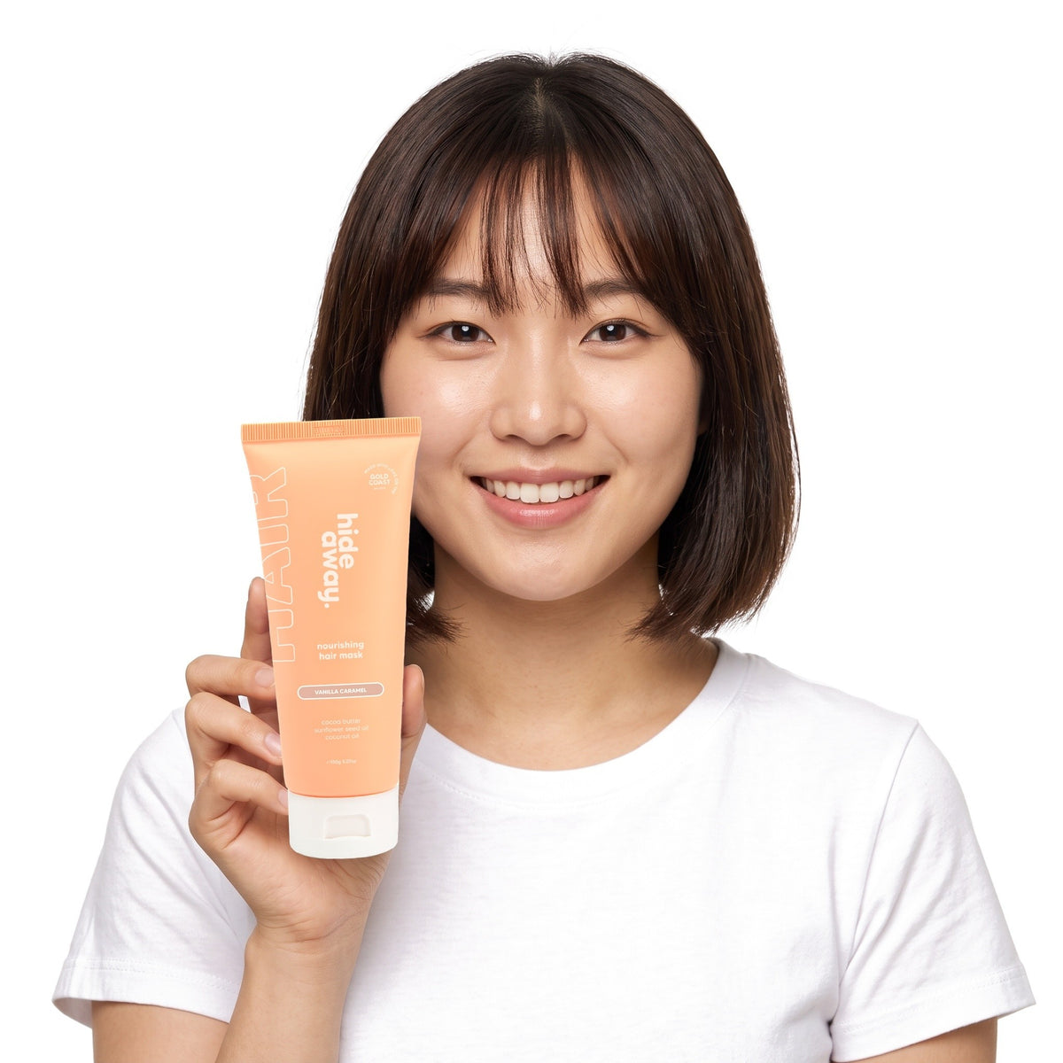 A smiling woman holding Hideaway. Vanilla Caramel hair mask