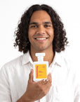 A smiling man holding Hideaway. Wild Mango perfume