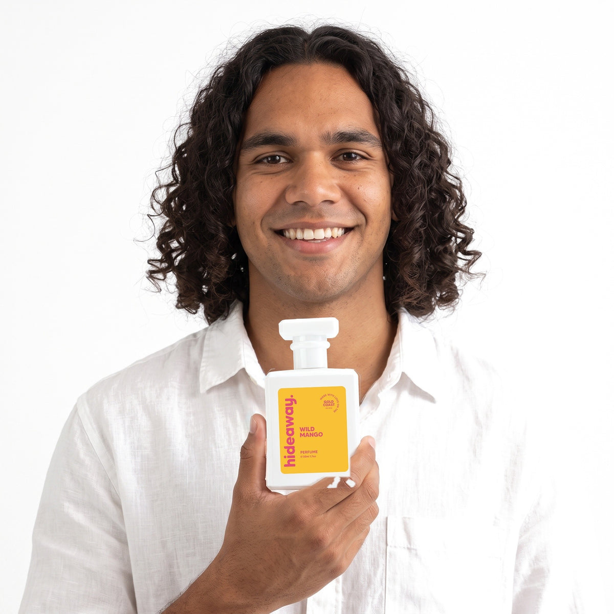 A smiling man holding Hideaway. Wild Mango perfume
